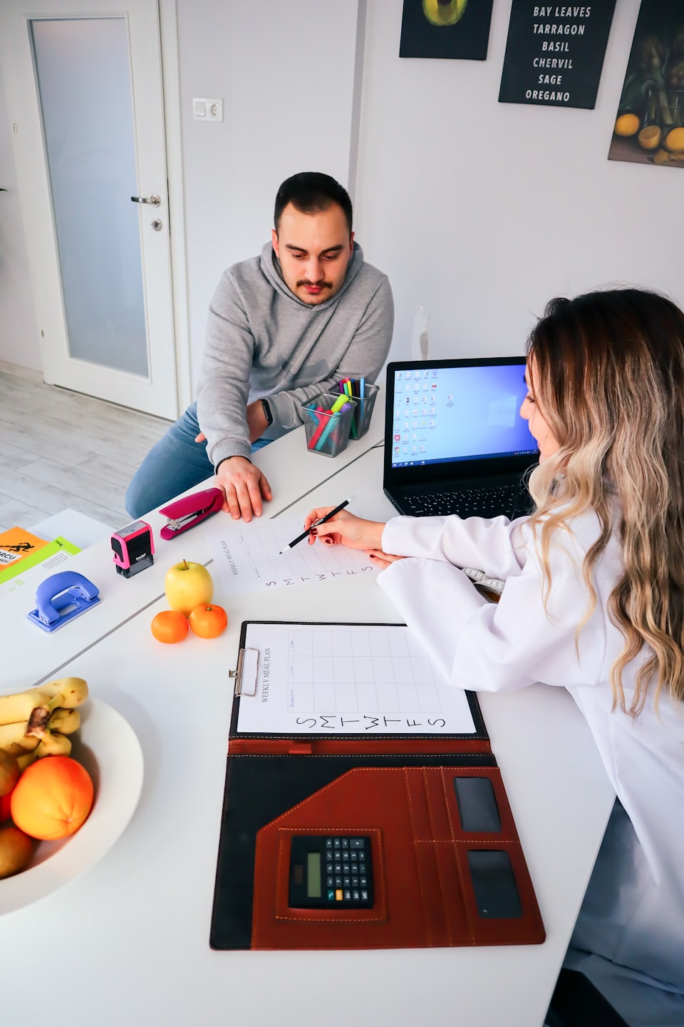 Voedingsdeskundige bespreekt maaltijdplan met cliƫnt in een consultatieruimte.