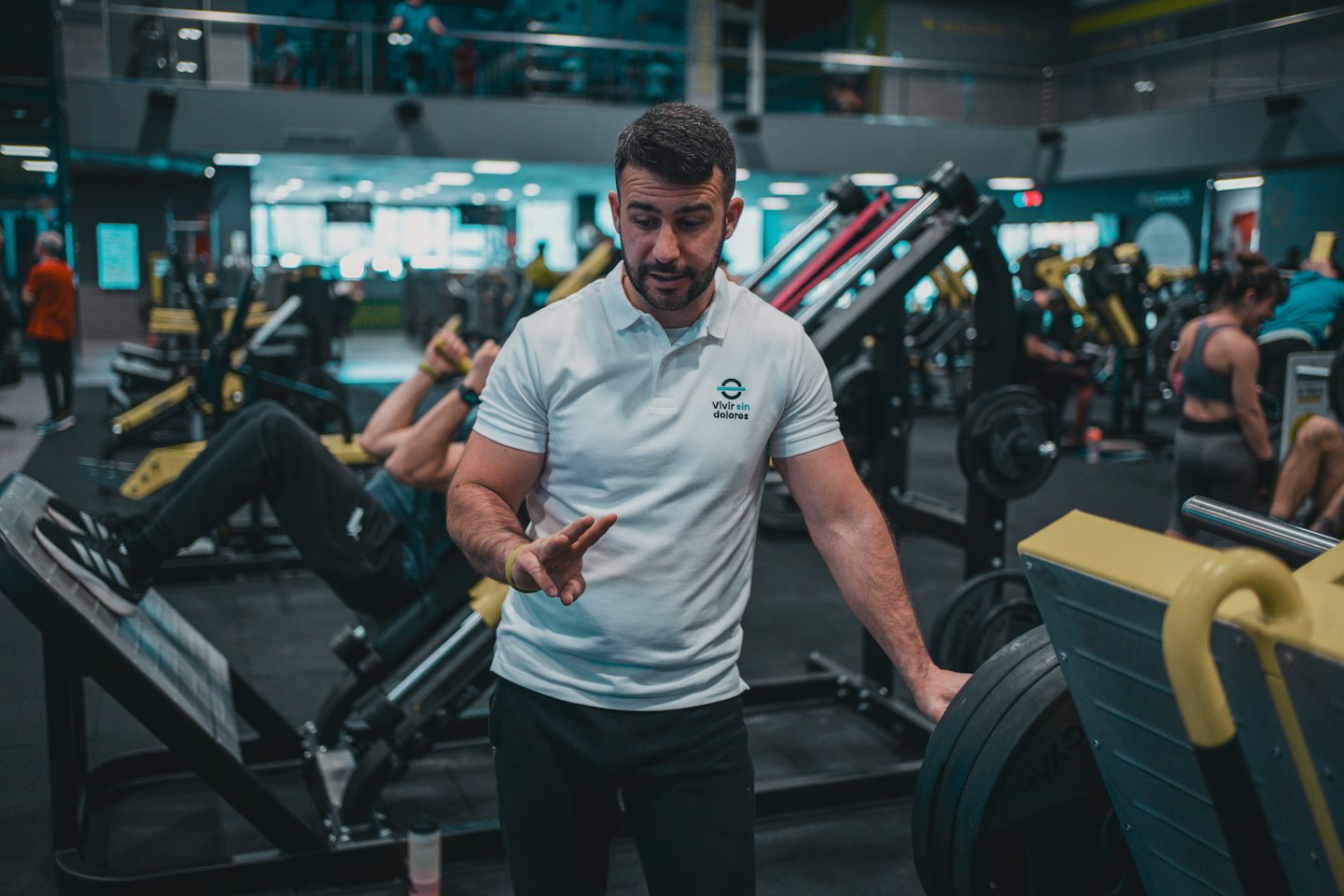 Personal trainer begeleidt cliënt op een leg press machine.